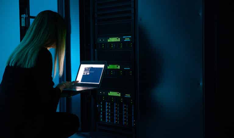 A female IT professional completing server maintenance using a laptop connected to an on-premise hybrid business server.