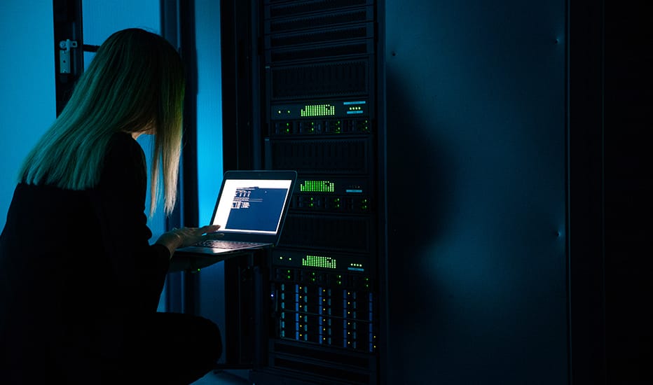 A female IT professional completing server maintenance using a laptop connected to an on-premise hybrid business server.
