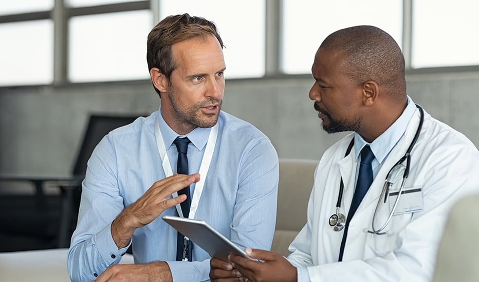 An managed security services consultant discusses HIPAA compliance strategies with an African American doctor who is concerned about a pending audit.