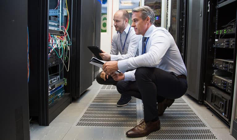 An IT director completes a network assessment and checks server configurations with his assistant.