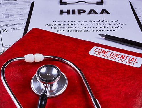 An angled photograph of various HIPAA compliance and security requirement documents.
