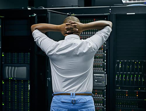 A stressed network administrator is seen restoring data from backups after a ransomware attack.