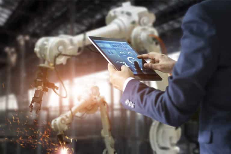 Automation depicted with a man controlling robotics via a tablet - Emerging Tech Trends of 2021