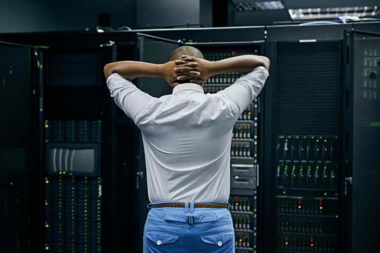 A man upset while looking at his server racks, wishing they had backup and disaster recovery planning