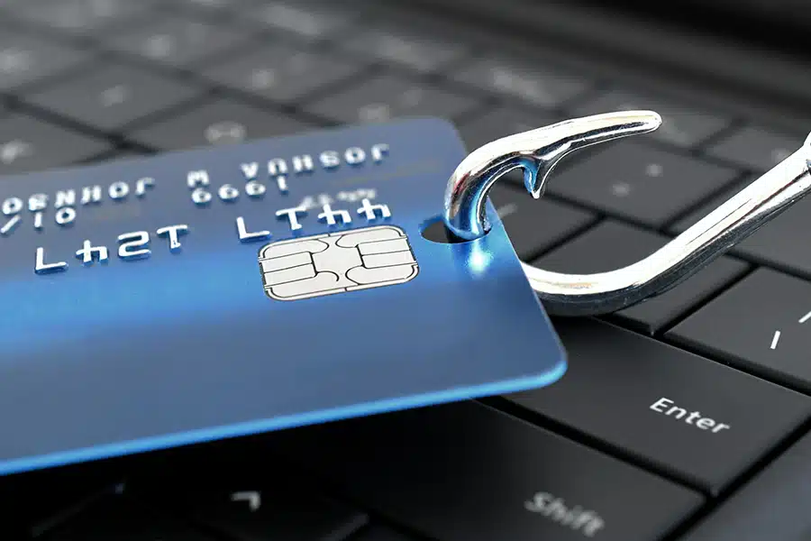 Phishing Definition: Someone who uses deception to gain credentials and access. This image shows a fishing hook going through a credit card.