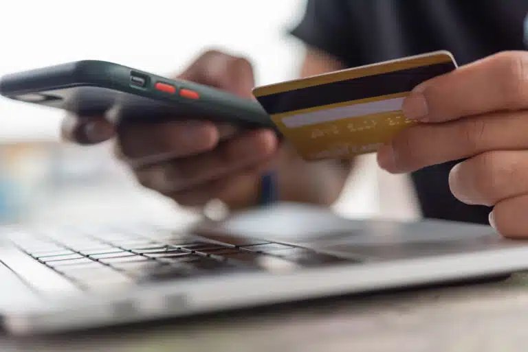 A person holding a phone and a credit card. Single sign on (SSO) can be a key piece of compliance regulations.